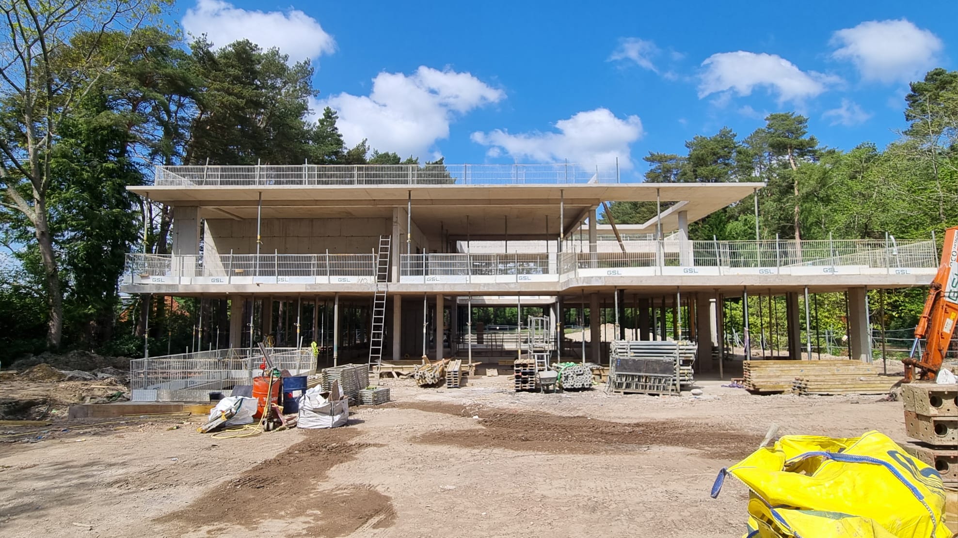 Struttura contemporanea in cemento armato di Eden House in fase di cantiere ad Ascot, Londra, con ampie terrazze a sbalzo immerse nel paesaggio naturale del golf club.